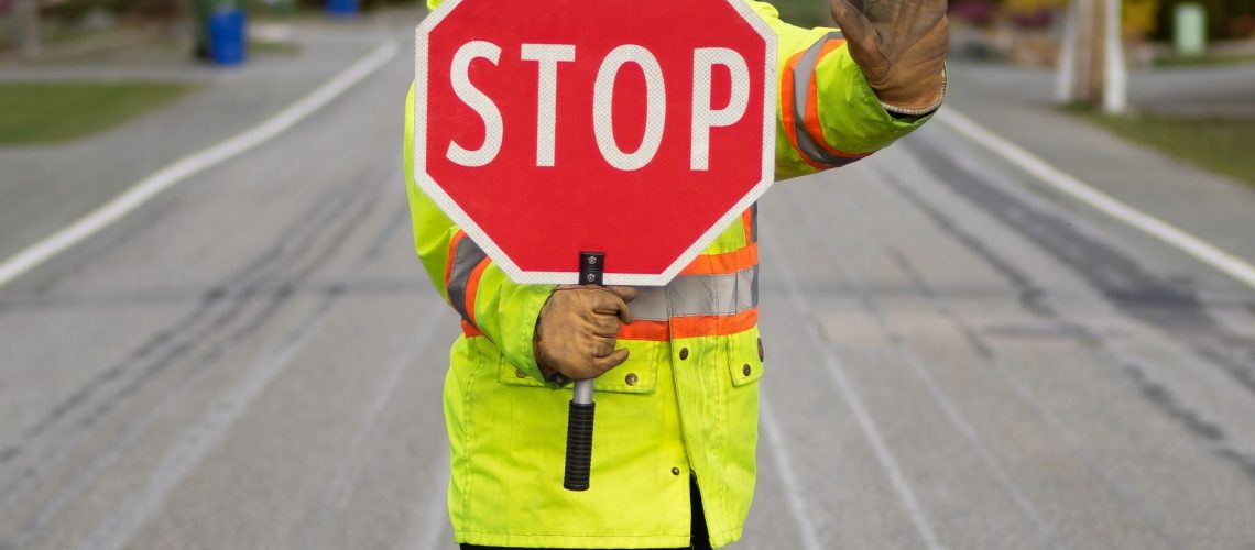 flagger holding stop sign and standing in the road