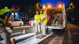 night road workers spraying paint onto the road