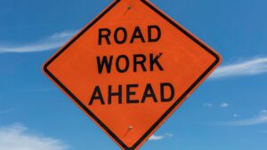 bright orange diamond road work ahead sign