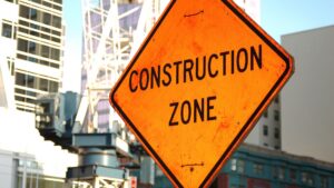 bright orange sign in road that reads "construction zone"