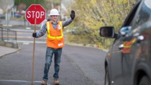 traffic flagger standing in the road with a stop sign and directing cars