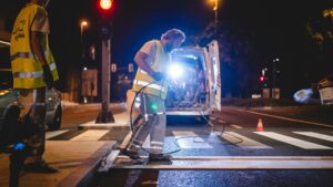 night road worker spraying paint onto the road