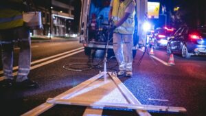 night roadworker painting road with high visibility vest on