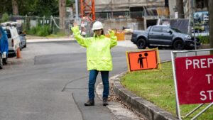 woman traffic controller on the road with PPE coat on.