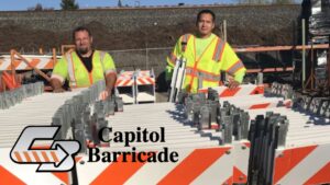 two construction workers standing by a truckload of barricades from capitol barricade